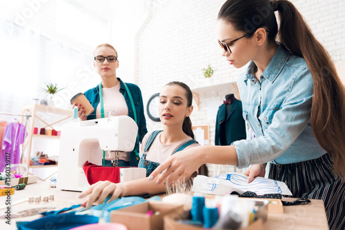 Three women at garment factory. They are looking at blueprints.