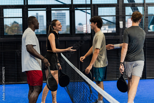 Group of friends enjoying padel tennis match, shaking hands over net