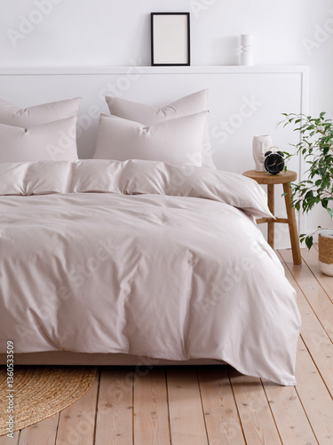 Bedroom with a double bed, fluffy down comforter with a beige duvet cover, four pillows, one beige cushion and wooden bedside table with vase. Close-up front view vertical photo. Suitable for mockup