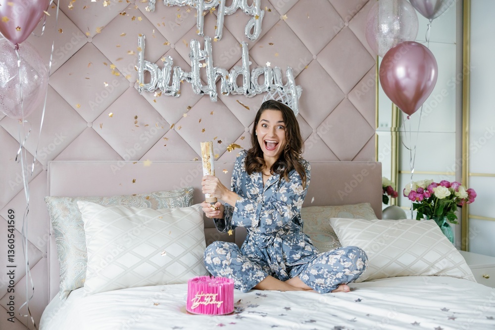 Fototapeta premium Young woman celebrating birthday opening firecracker on bed