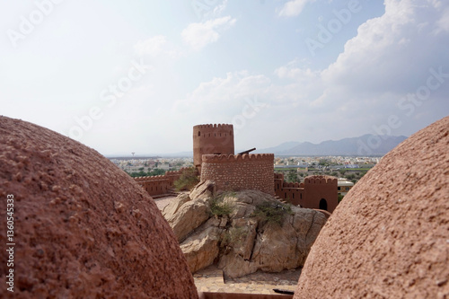 Magnificent Nakhal Fort surrounded by rugged mountains under clear sky in Al Batinah Region, Sultanate of Oman - Ancient Arabic fortress architecture