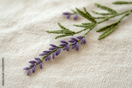 Close-up of delicate hand-embroidered lavender sprig on beige fabric.