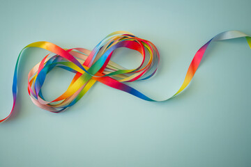 Autism acceptance month, Autism awareness day concept. Rainbow colors ribbons in shape of infinity loop on blue background. Infinity is symbol of autism disorder, adhd, neurodiversity