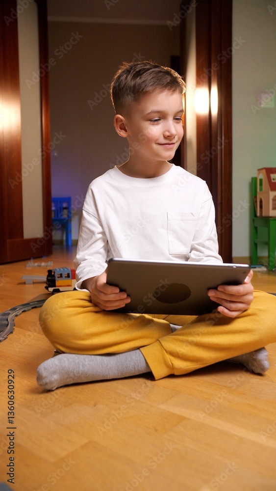 Boy happily using a digital tablet in his playroom, surrounded by toys, exploring technology for education and fun, embodying the modern tech-savvy child lifestyle Boy happily using a digital tablet in his playroom, surrounded by toys, exploring technology for education and fun, embodying the modern tech-savvy child lifestyle