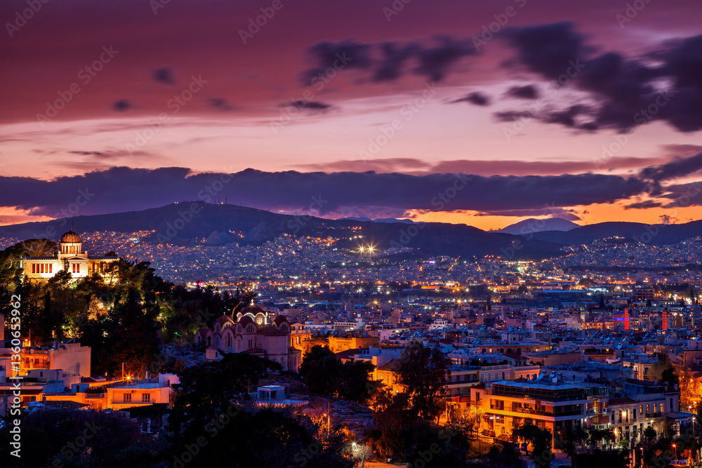 Breathtaking view of Athens at sunset, with illuminated buildings and a dramatic twilight sky. A stunning blend of history and modern city lights.