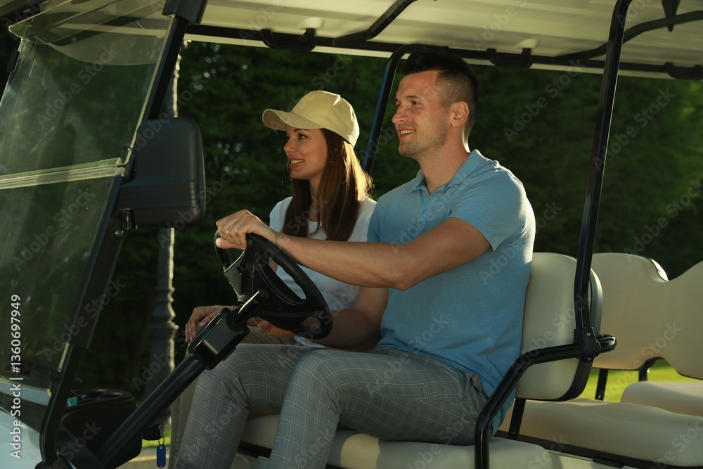 Obraz premium Happy couple driving golf cart in park