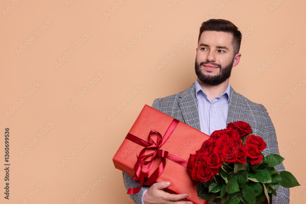 Happy man with bouquet of red roses and gift box on beige background, space for text Happy man with bouquet of red roses and gift box on beige background, space for text