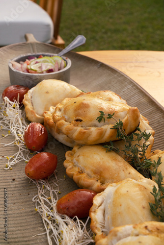 Hot finger food with a rustic presentation. Closeup view of gourmet traditional crispy meat empanadas on the table outdoor	
