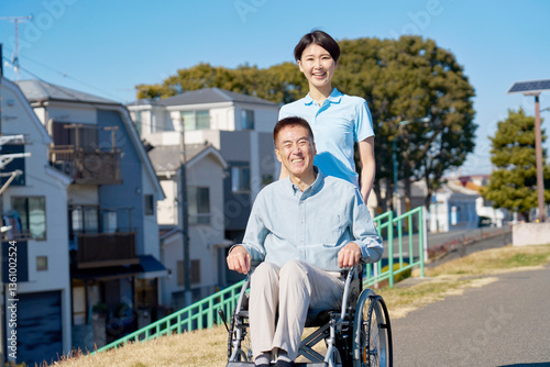 車椅子に乗った中年の女性と介護士　屋外　ポートレート　カメラ目線