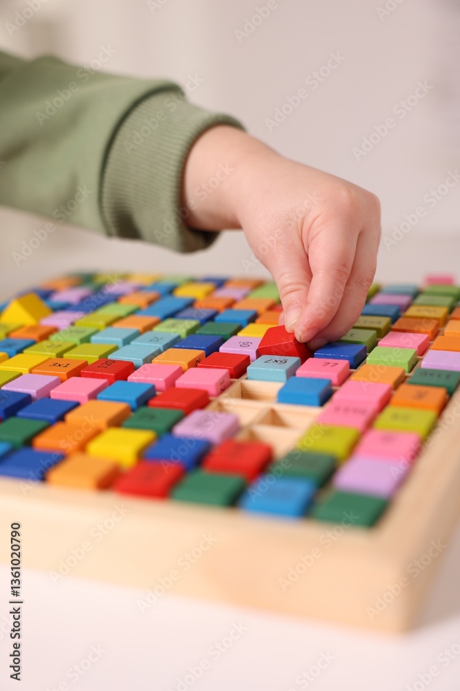 Fototapeta premium Motor skills development. Little boy playing with Times table tray indoors, closeup
