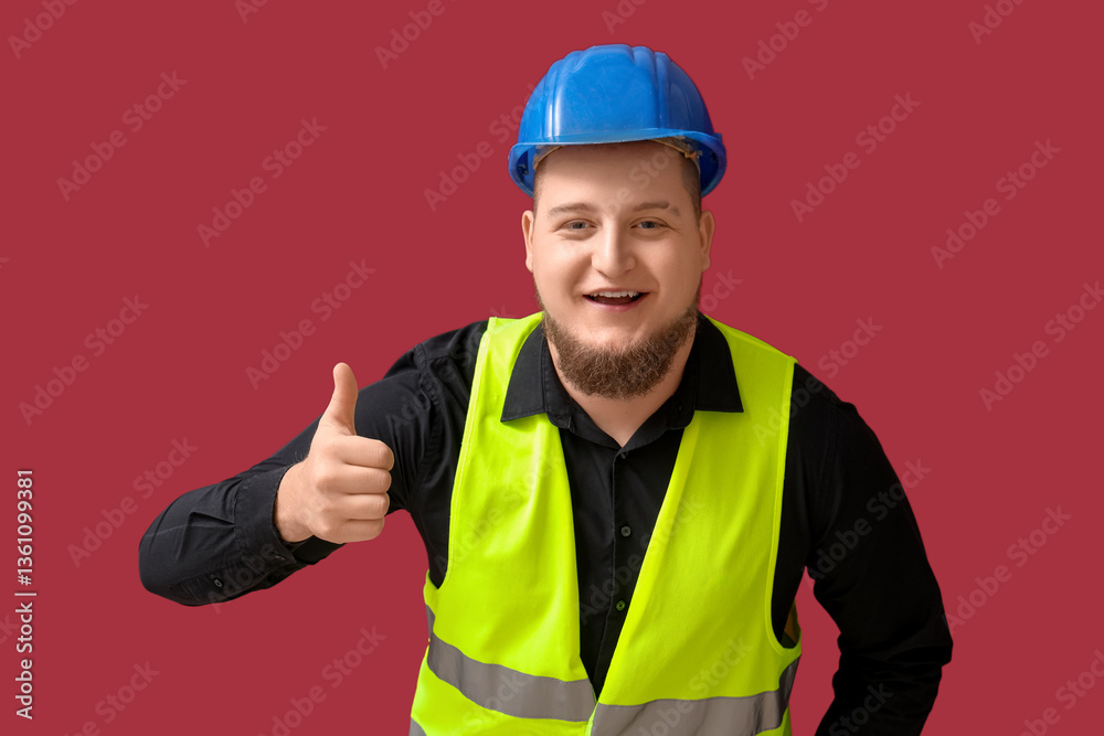 Male engineer showing thumb-up gesture on dark red background Male engineer showing thumb-up gesture on dark red background