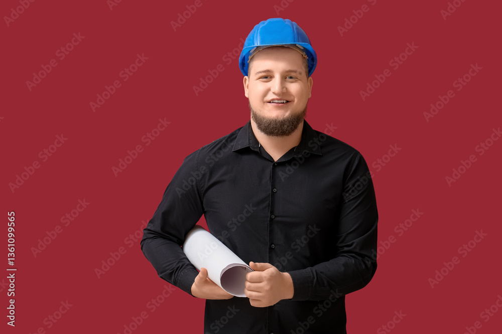 Young male engineer with drawing on dark red background Young male engineer with drawing on dark red background
