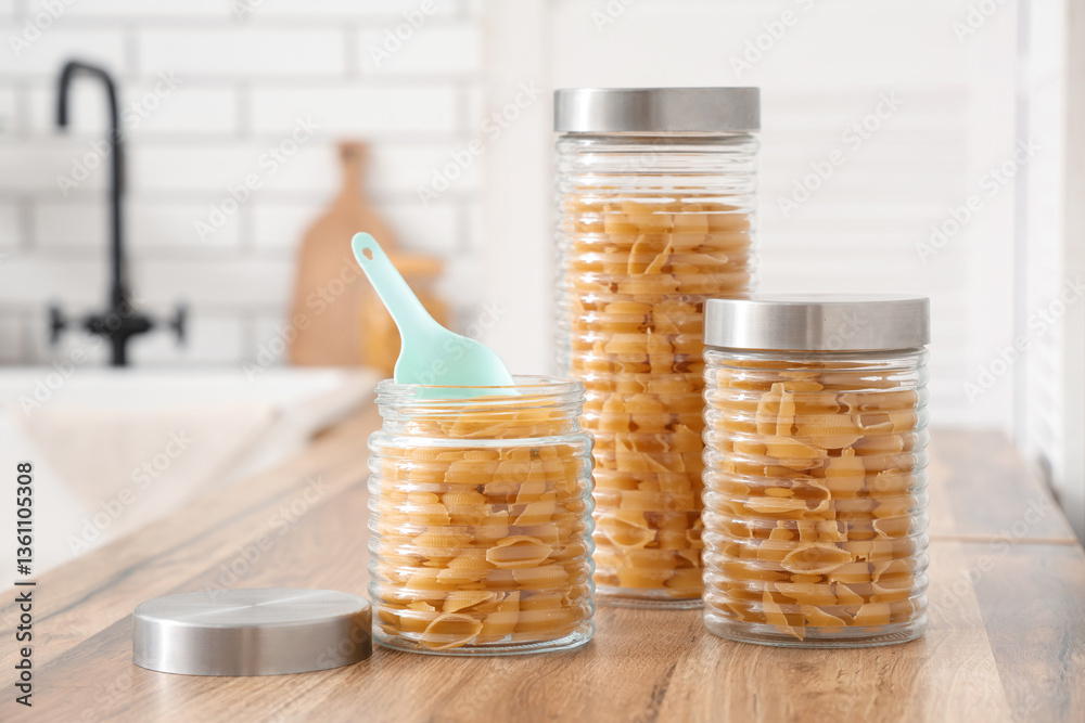 Different jars with raw pasta shells on table in kitchen Different jars with raw pasta shells on table in kitchen