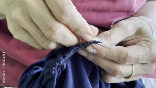 Closeup of craftswoman hands sewing with needle and thread. Female hand sews clothes