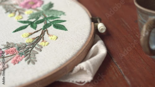 Beautiful embroidery flowers on cotton fabric. Product of needlework on a piece of embroidery. Needlework is decorative sewing and textile arts handicrafts. How to stitch embroider flowers on clothes.