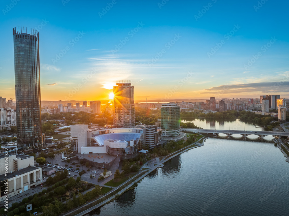 Fototapeta premium Yekaterinburg city and pond aerial panoramic view at summer or early autumn sunset. Night city in the early autumn or summer.