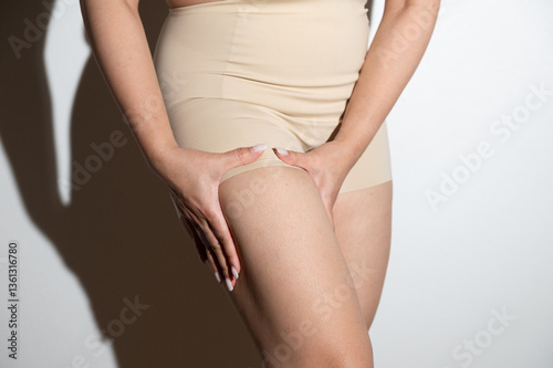 Woman checking thigh skin for cellulite photo