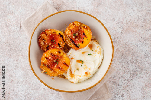 Delicious grilled peaches with mascarpone cream, honey syrup, crumbs and thyme in a bowl on a concrete background. Summer dessert. Top view.