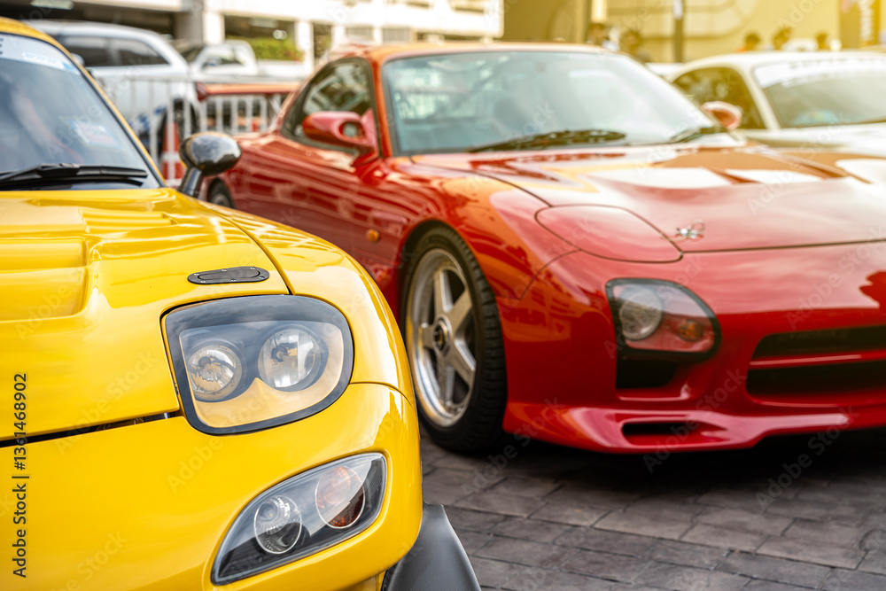 Modern yellow and red cars close-up view of headlights and sun rays parked in row outdoor, brand new cars for sale. Modern yellow and red cars close-up view of headlights and sun rays parked in row outdoor, brand new cars for sale.