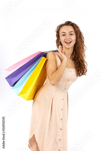 Young beautiful girl with curly hair with bags and purchases from the store. Figure isolated on white background.