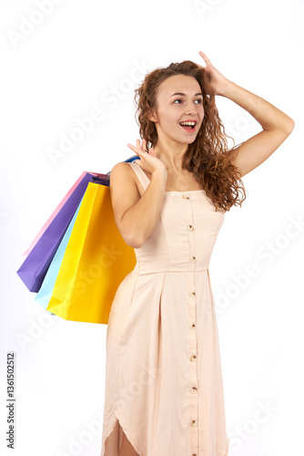 Young beautiful girl with curly hair with bags and purchases from the store. Figure isolated on white background.