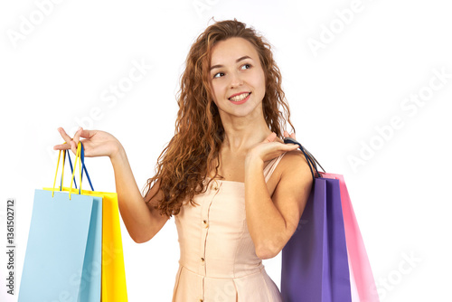 Young beautiful girl with curly hair with bags and purchases from the store. Figure isolated on white background.