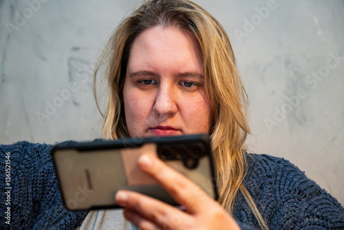 Engaged mother enjoying quiet time while checking her phone in a cozy background setting