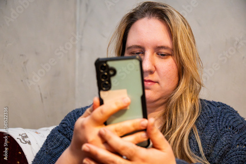 Caucasian mother using smartphone while relaxing at home in a cozy environment