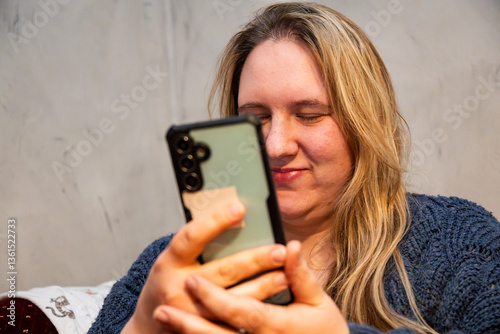 Mother engaging with her smartphone in a cozy indoor setting, enjoying a moment of connection and leisure