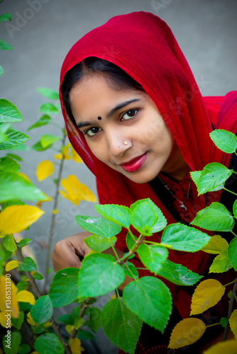 A beautiful young woman is looking through the green and yellow leaves of spring. Fashion model portrait.