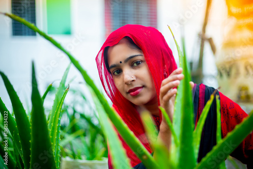 Portrait of a beautiful young Asian woman wearing a red dress in a green aloe vera garden. Fashion model portrait.