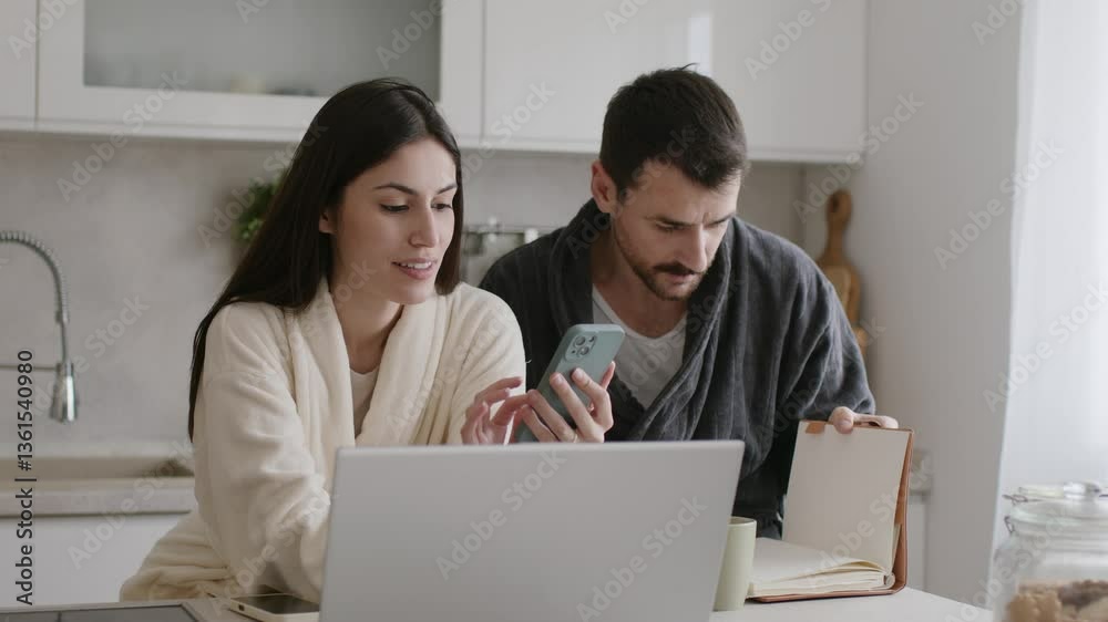 Couple wearing bathrobes working from home in the morning using laptop and smartphone. 4k video Couple wearing bathrobes working from home in the morning using laptop and smartphone. 4k video