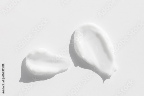Samples of white cosmetic skin cream, foam on light gray background, top view macro.