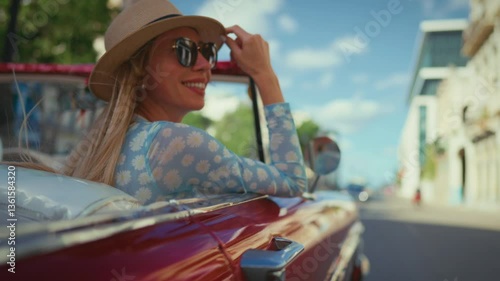 Traveling and freedom, joyful blonde woman riding retro car and smiling, summer. Merry vacation and holidays, beautiful female passenger of luxury cabriolet enjoying good mood and landmarks of town