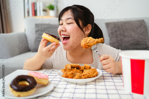 A woman is happily eating fried chicken and donuts on a plate.