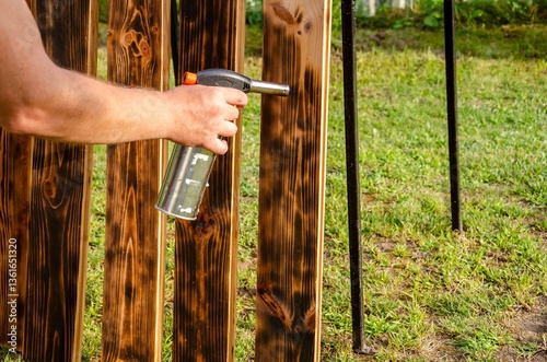 Treating wooden planks with fire from a gas.
