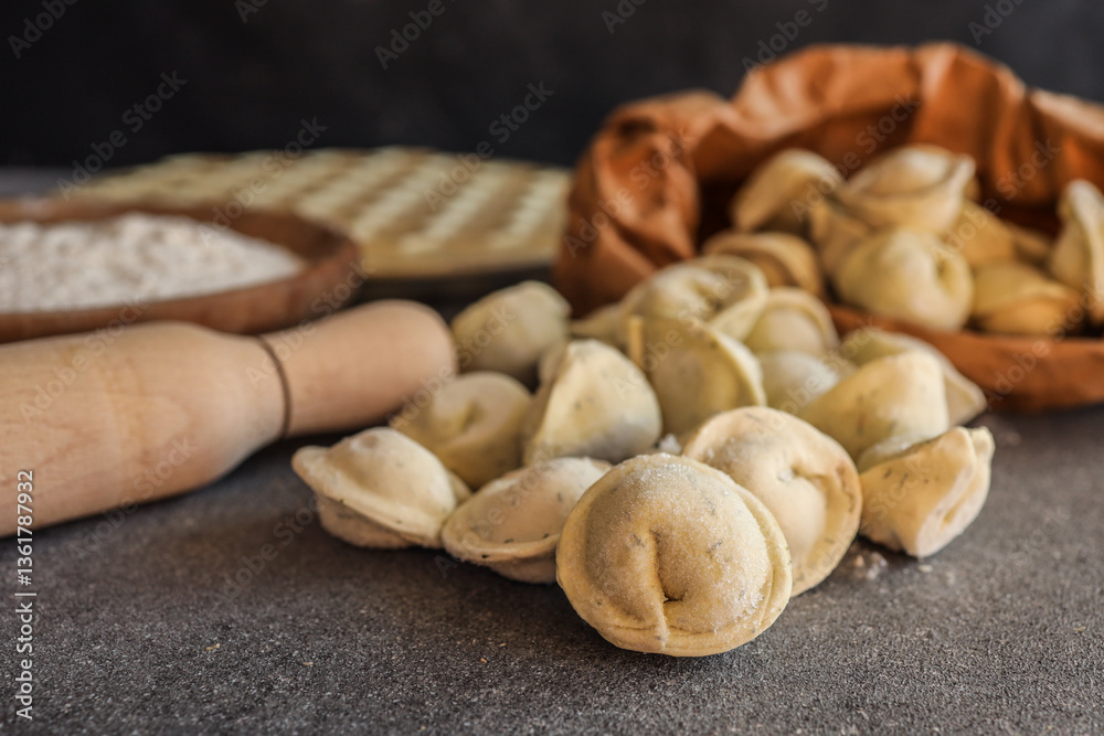 Obraz premium Close-up of frozen tortellini pasta on a kitchen counter with rolling pin, flour, and paper bag in the background, ready for cooking or homemade preparation