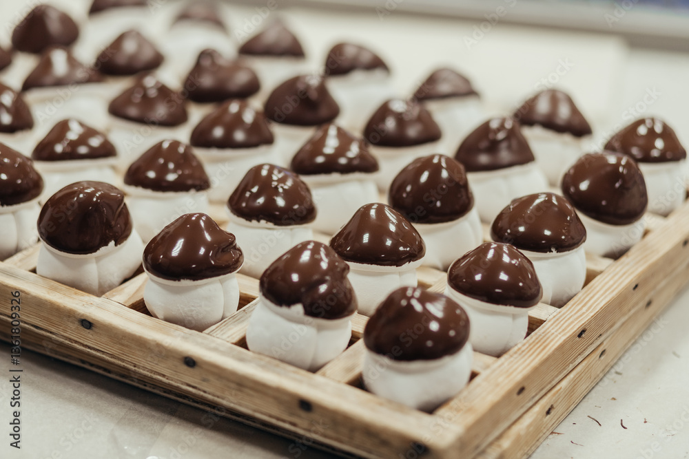 Marshmallow sweets in the form of mushroom in wooden tray on industry. Brown-white boletus.