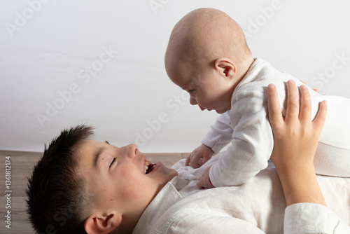 Older brother playing with his baby sibling lying on the floor
