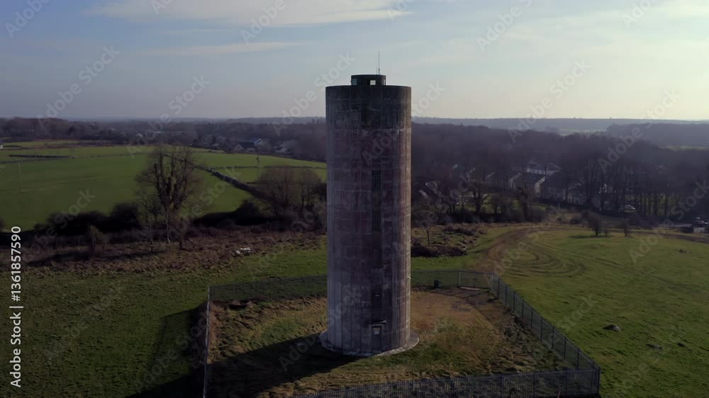 Establishing aerial shot of a cylindrical water tower, well-framed and orbiting to reveal the surrounding Irish landscape Establishing aerial shot of a cylindrical water tower, well-framed and orbiting to reveal the surrounding Irish landscape