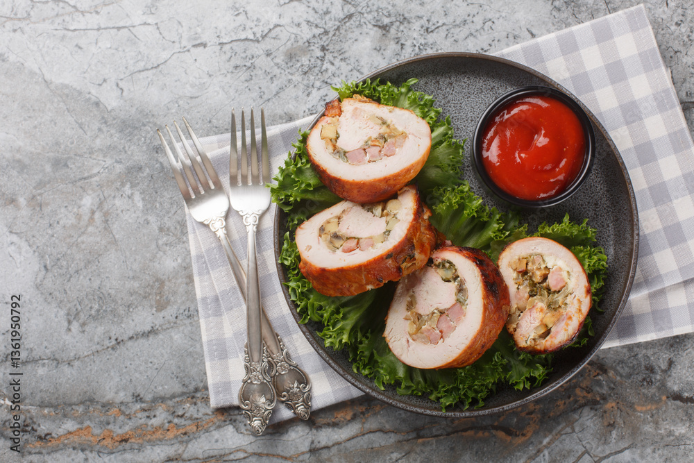 Juicy turkey roll with bacon, onions and mushrooms close-up in a plate on the table. Horizontal top view from above