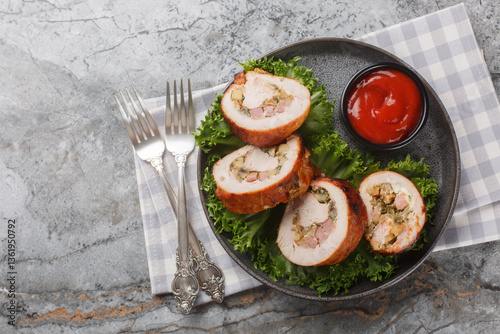 Juicy turkey roll with bacon, onions and mushrooms close-up in a plate on the table. Horizontal top view from above