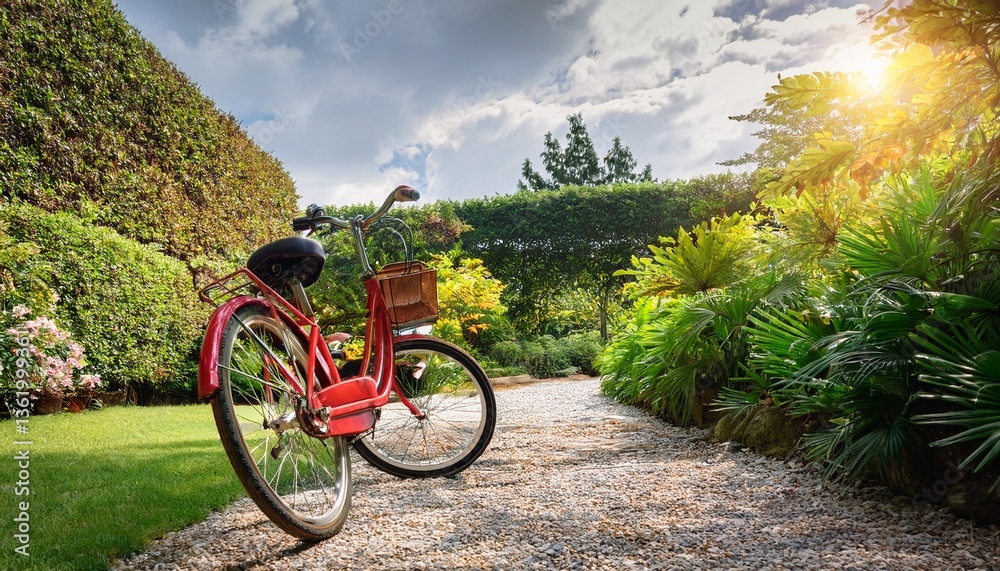 Fototapeta premium red bicycle parked on gravel path in garden ready for outdoor adventure
