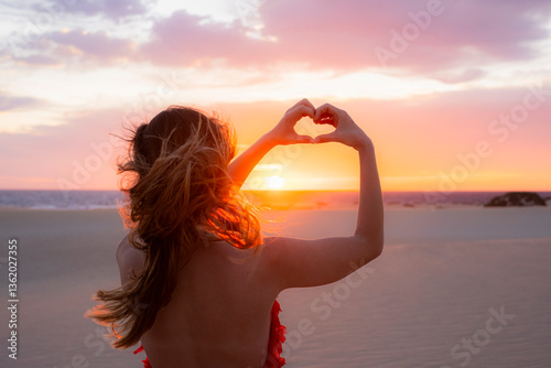 Woman forming a heart with her hands at dawn
