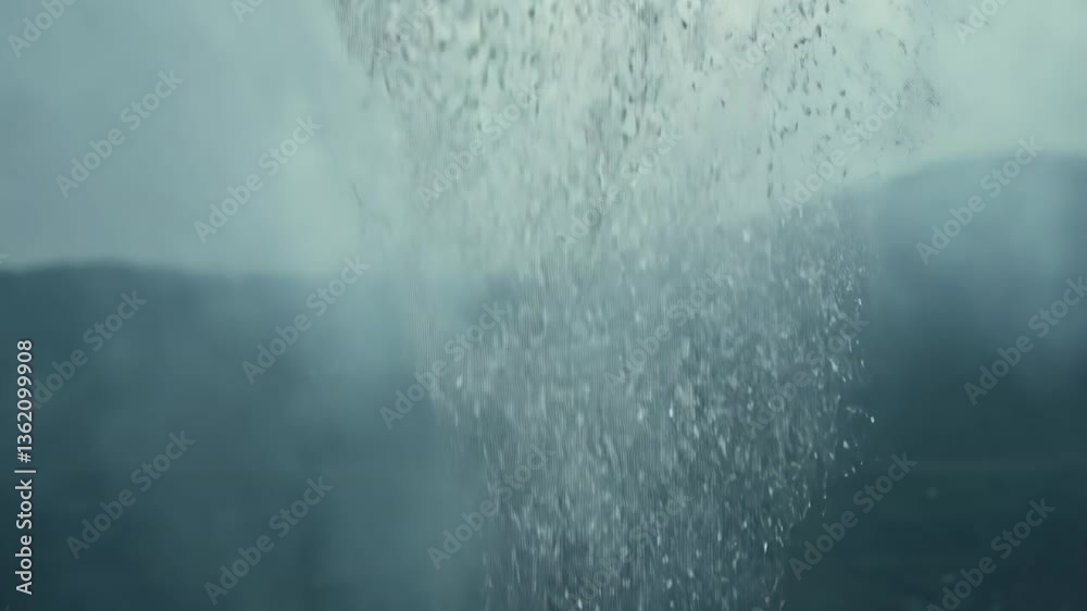 A column of water bursts upward from a deep body, its spray catching the light in a mesmerizing display of nature’s raw power. The scene feels both tranquil and intense.
