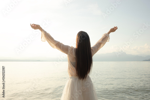 woman takes a breath in front of the sun at the sea