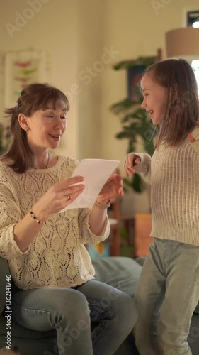 Girl holds a card with a picture of a heart and gives it to her mother on Mother's Day.