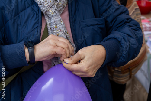 Two people tying a purple balloon at an event