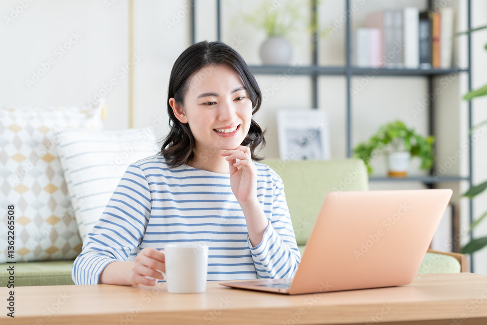 リビングでパソコンを使う若い女性 リビングでパソコンを使う若い女性