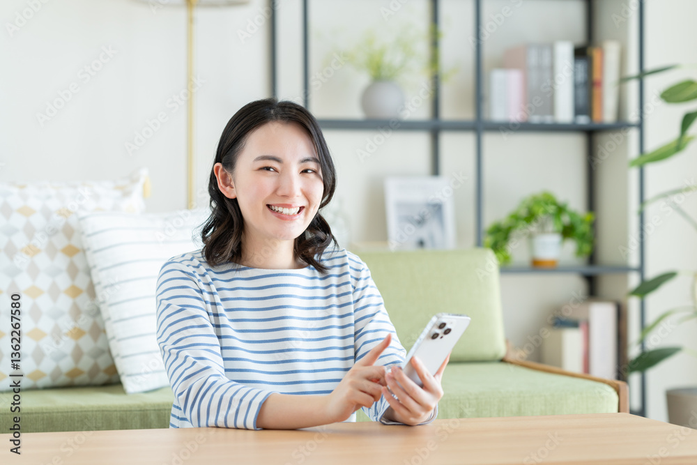 リビングでスマホを使う若い女性 リビングでスマホを使う若い女性